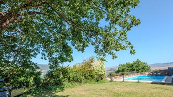Ein Garten mit Schwimmbad, Rasen und Blick auf ferne Hügel.