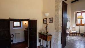 A room with a wooden door, a radiator, a table with a lamp, and a chair. - Tripla con Bagno in Camera (Nicosia)