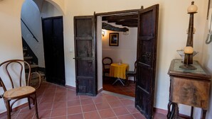 A hallway with a chair, a table with a yellow tablecloth, and a rustic lamp. - Tripla con Bagno in Camera (Nicosia)