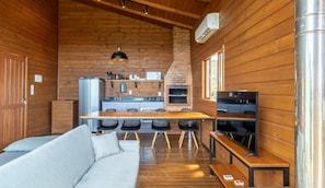 A cozy cabin interior with a wooden interior, a dining area, a sofa, and a television. - Cabana na serra com linda vista VST012 (Anitapolis)
