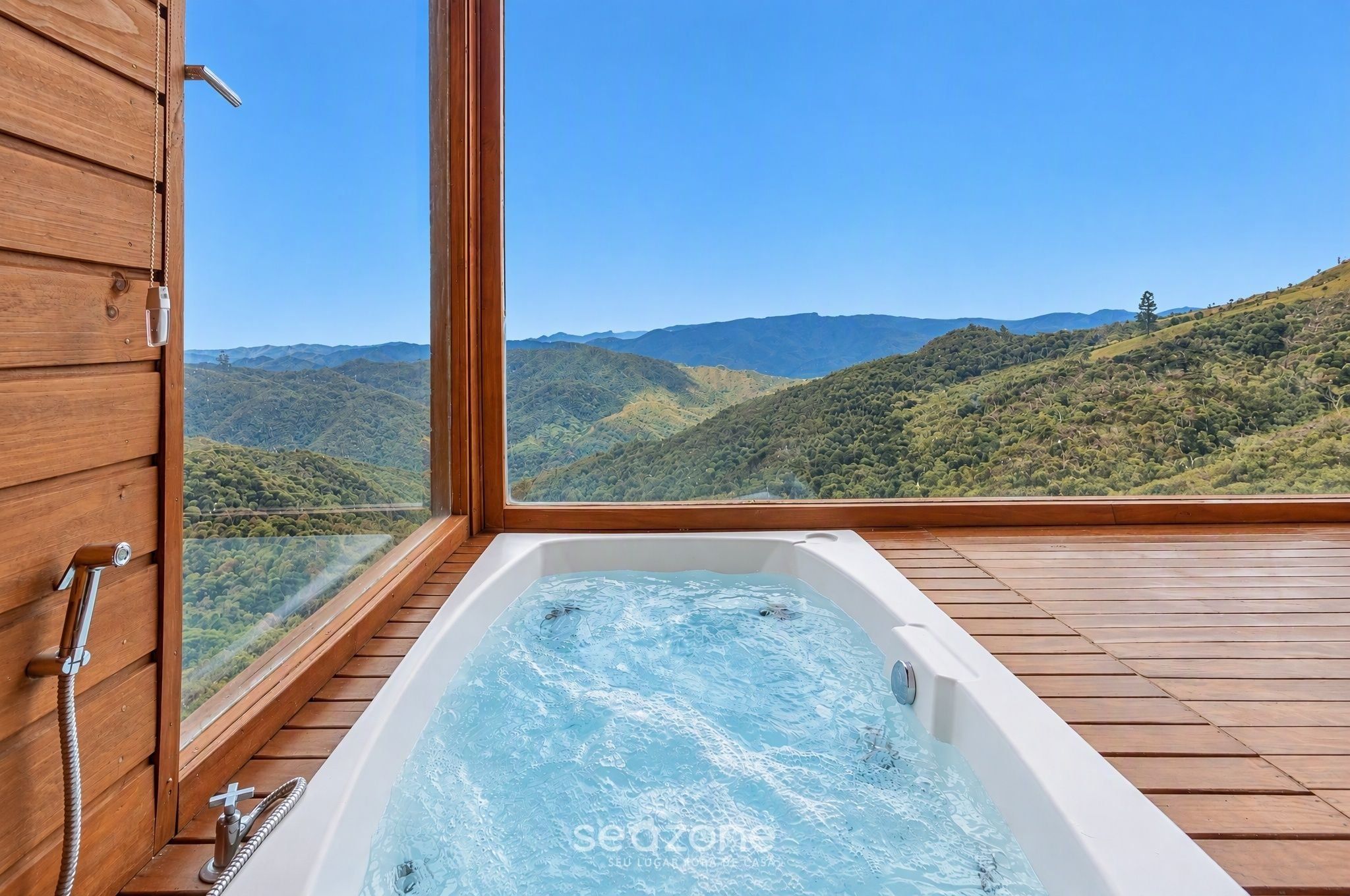 Un jacuzzi con terraza de madera y vista a un paisaje montañoso.