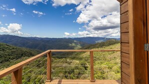 A wooden balcony with a metal railing overlooking a mountainous landscape. - Cabana na serra com linda vista VST012 (Anitapolis)