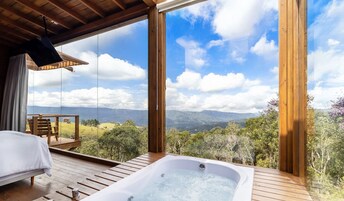 A wooden deck with a hot tub, a bed, and a view of mountains.