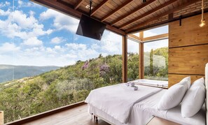 A bedroom with a large window offering a view of a mountainous landscape.