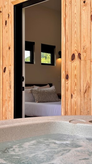 A bedroom with a bed, two windows, and a view of greenery outside.
