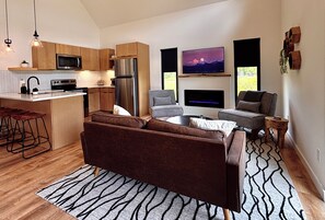 Een moderne keuken met een centraal eiland, een zithoek met een bank en een woonkamer met een open haard.