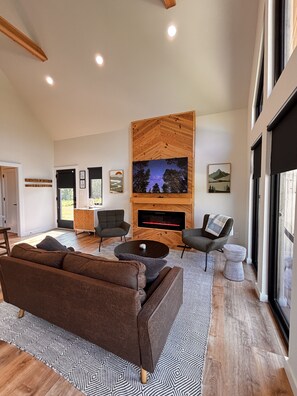 A modern living room with a fireplace, comfortable seating, and artwork on the walls. - Knob Hill - River BEACH, Hot Tub, 360 VIEWS, Romantic (Stanton)