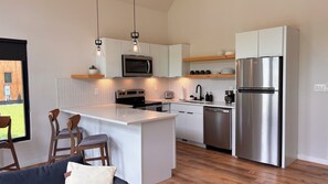 A modern kitchen with a central island, stainless steel appliances, and a herringbone-patterned backsplash.