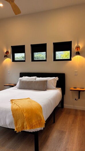 A bedroom with a bed, bedside tables, a ceiling fan, and wall-mounted picture frames.