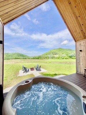 A hot tub with a view of a grassy field and hills.