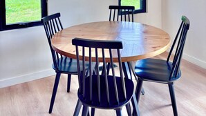 A dining area with a round wooden table and four black chairs. There are three hexagonal wooden shelves on the wall, each holding a plant and a small decorative item. - Perfect Perch - RARE River with BEACH, Sunsets and Stars, Hot Tub, Mountain View (Stanton)
