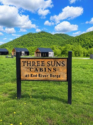 Puinen kyltti, jossa lukee: ”Three Suns Cabins at Red River Gorge”, ja taustalla näkyy mökkejä.