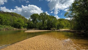 A riverbank with clear water, surrounded by lush greenery and trees. - Trail Tamer - Gorgeous 360 Views, RIVER with sandy BEACH, Hot Tub, RRGorge (Stanton)