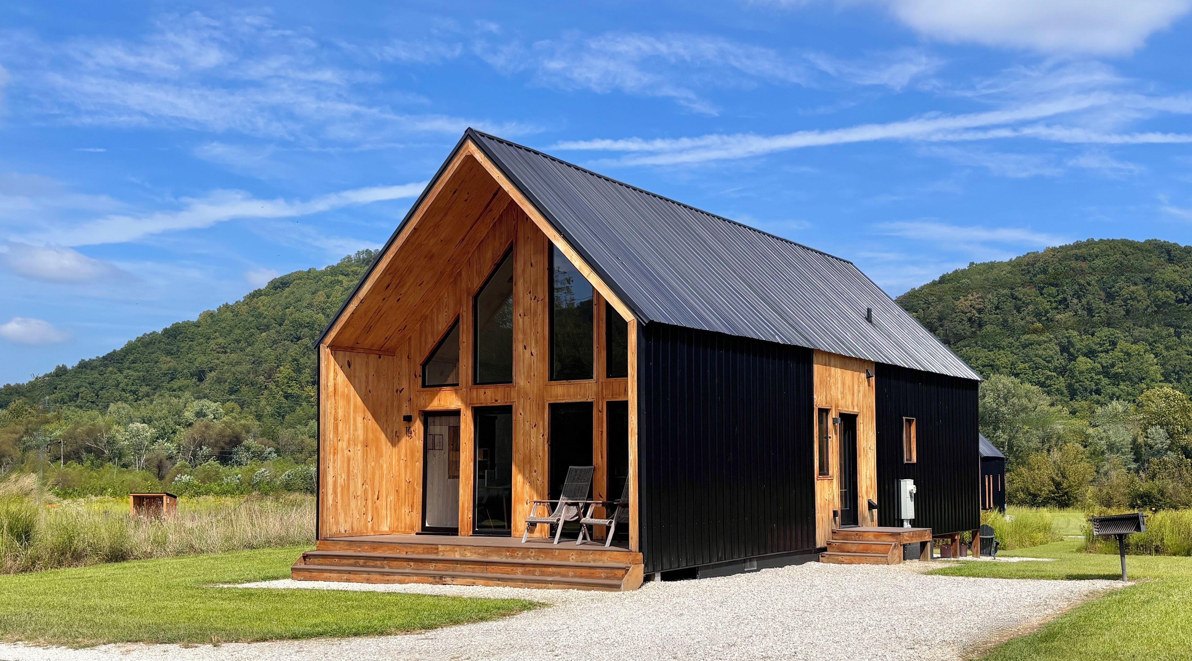 Een houten chalet met een ruim terras en een oprit van grind.