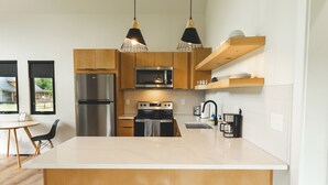 A modern kitchen with wooden cabinets, stainless steel appliances, and a central island with bar stools. - Trail Tamer - Gorgeous 360 Views, RIVER with sandy BEACH, Hot Tub, RRGorge (Stanton)