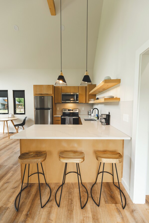 A modern kitchen with wooden cabinets, stainless steel appliances, and a central island with bar stools.