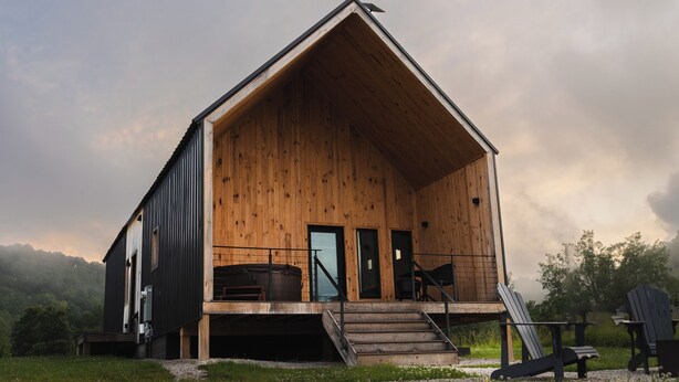 A wooden cabin with a sloped roof, a front porch, and a staircase leading to the entrance. - Trail Tamer - Gorgeous 360 Views, RIVER with sandy BEACH, Hot Tub, RRGorge (Stanton)
