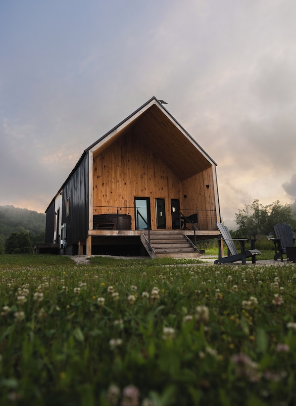 A wooden cabin with a sloped roof, a front porch, and a staircase leading to the entrance.