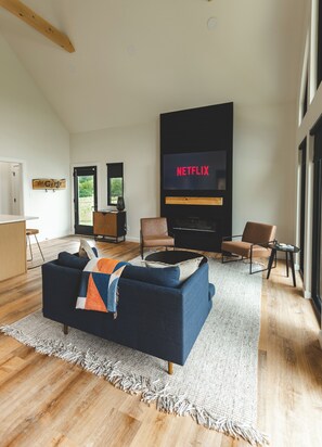 A modern living room with a dark blue sofa, a flat-screen TV, and a fireplace.