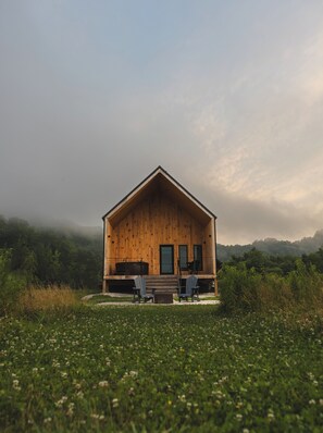 A wooden cabin with a porch, two chairs, and a table.