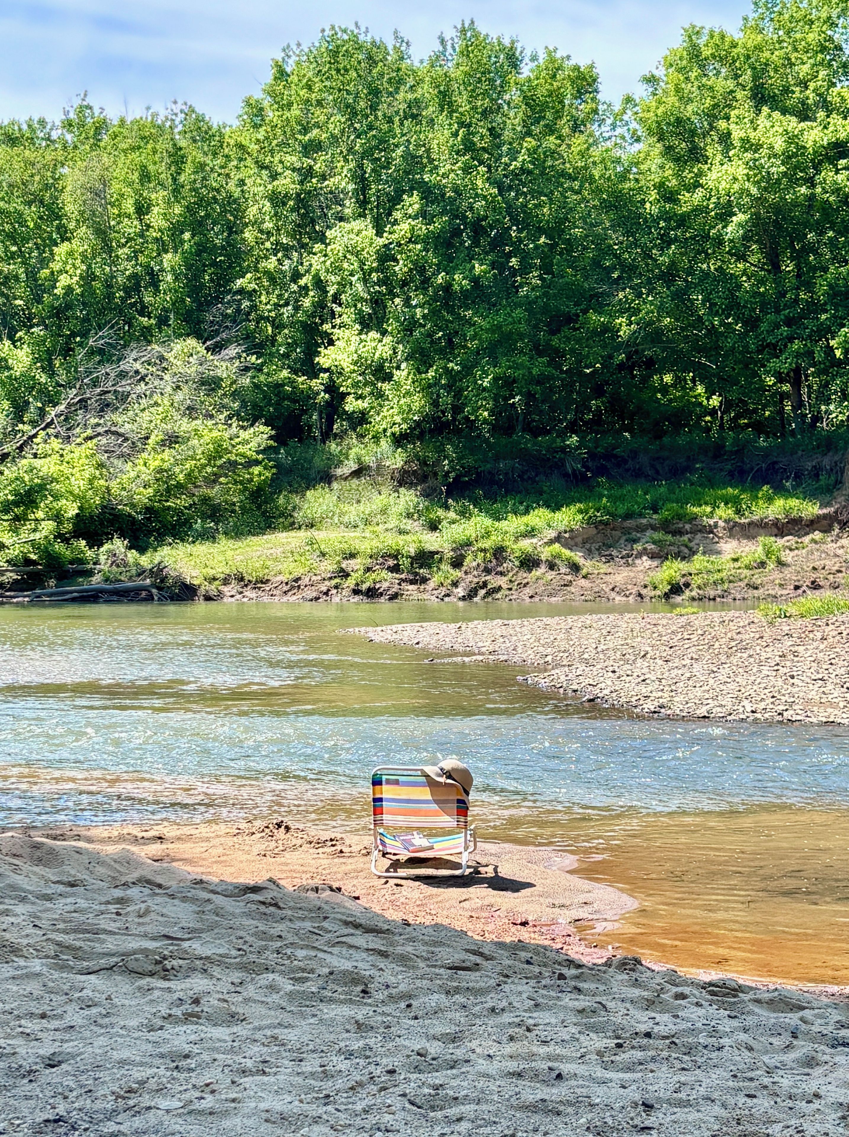 Une rive avec une chaise et un chapeau posés sur le sable.
