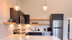 Una cocina moderna con una isla grande, electrodomésticos de acero inoxidable e iluminación colgante.