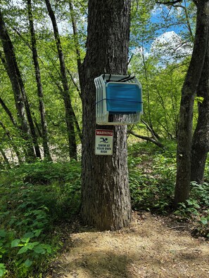 Un árbol con un recipiente azul y una señal de advertencia.