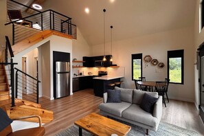 A modern interior with a kitchen, dining area, and a staircase leading to an upper level.