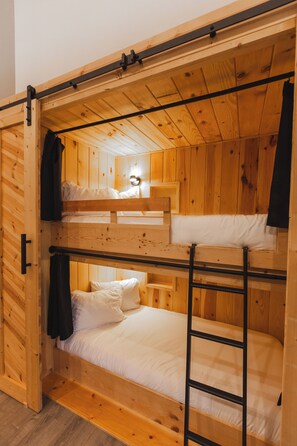 A bunk bed room with wooden walls and a ladder.