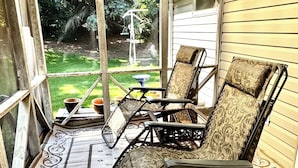 A covered porch with two chairs, a table, and a hanging light fixture. - 3-bedroom house in delightful Mapleton with AC, WiFi. Unwind and enjoy! (Mapleton)