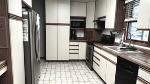 A kitchen with white cabinets, a refrigerator, a dishwasher, and a microwave. - 3-bedroom house in delightful Mapleton with AC, WiFi. Unwind and enjoy! (Mapleton)