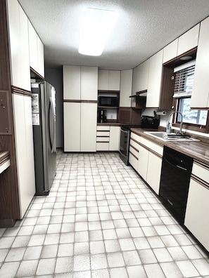 A kitchen with white cabinets, a refrigerator, a dishwasher, and a microwave. - 3-bedroom house in delightful Mapleton with AC, WiFi. Unwind and enjoy! (Mapleton)