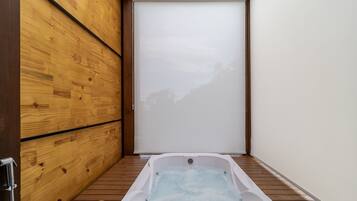 A small, enclosed hot tub area with wooden walls and a sliding door.