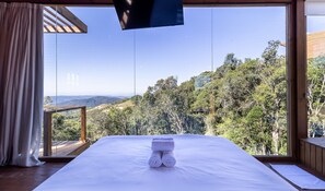 A bedroom with a large window offering a view of a forested landscape. - Cabana c\ lareira prox. de Florianópolis VST033 (Anitapolis)