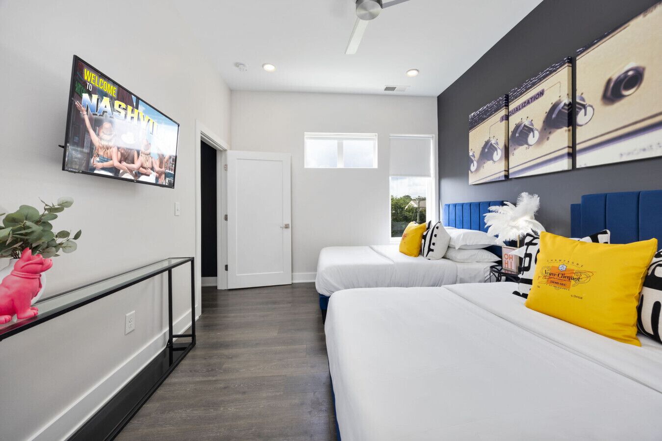Ein modernes Hotelzimmer mit zwei Betten, einem an der Wand befestigten Fernseher und einem großen Fenster.