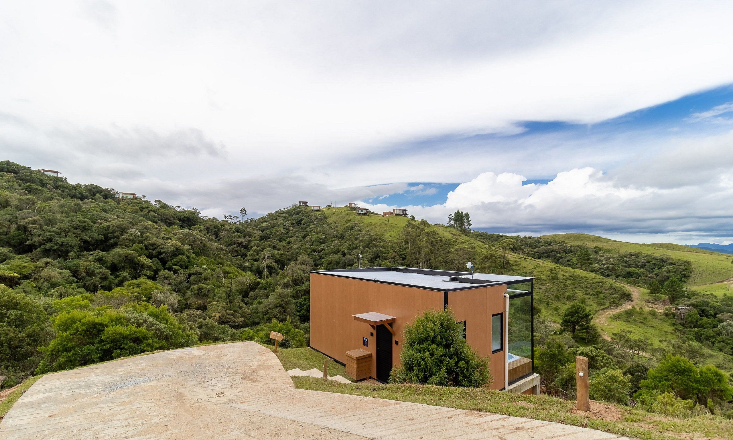 Um edifício moderno, térreo e com telhado plano, localizado numa encosta coberta por vegetação exuberante.