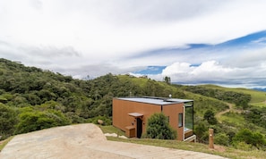 Un bâtiment moderne, de plain-pied, doté d’un toit plat et situé sur une colline, au milieu d’une végétation luxuriante.