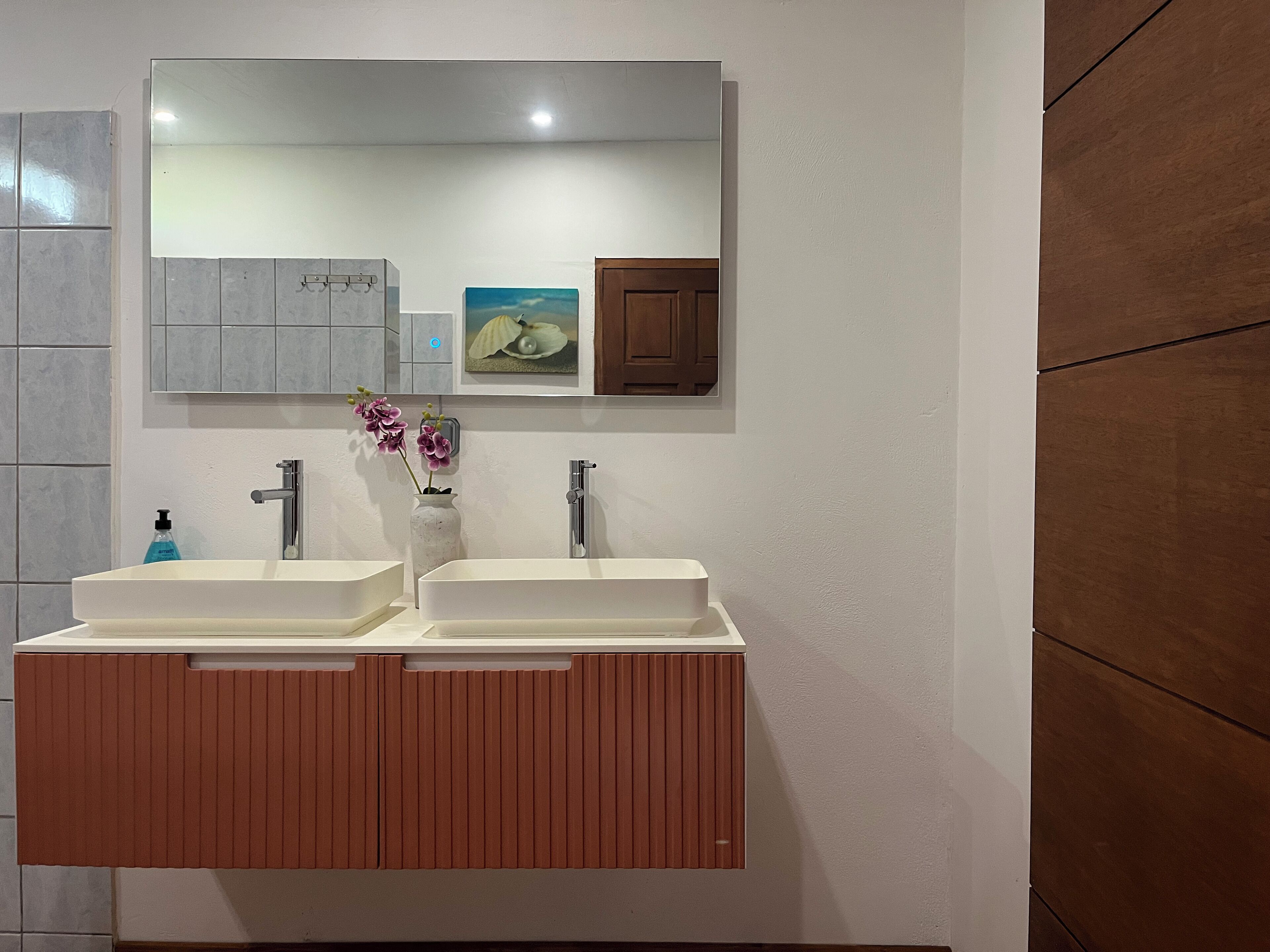 Une salle de bain avec deux lavabos, un miroir et un meuble-lavabo en bois.