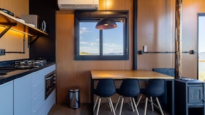 A compact kitchen with a stove, oven, and a window overlooking a landscape.