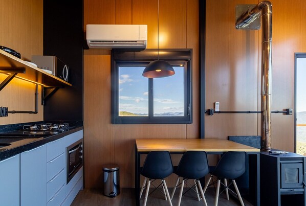 Cozinha compacta com fogão, forno e janela com vista para a paisagem.