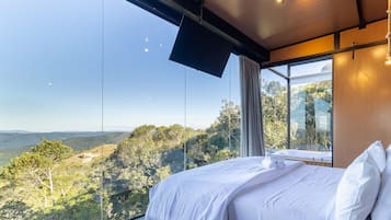 Un dormitorio con un amplio ventanal que ofrece vistas a un paisaje montañoso.