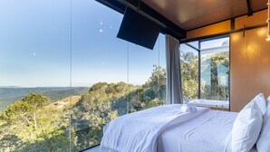 Un dormitorio con un amplio ventanal que ofrece vistas a un paisaje montañoso.