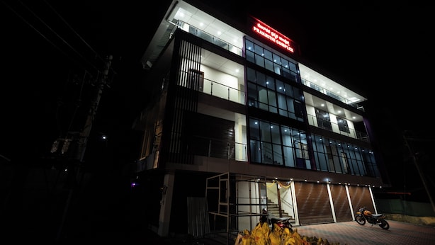 A modern building with a prominent sign, large windows, and a motorcycle parked in front. - Golden Crest Residences (Madikeri)