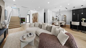 A modern living room with a large L-shaped sectional sofa, a coffee table, and a staircase leading to an upper floor.