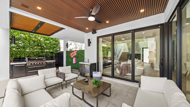A modern outdoor living area with a sofa, chairs, a coffee table, and a grill.