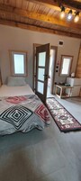 Quarto com cama, porta de madeira, mesa pequena e tapete estampado.