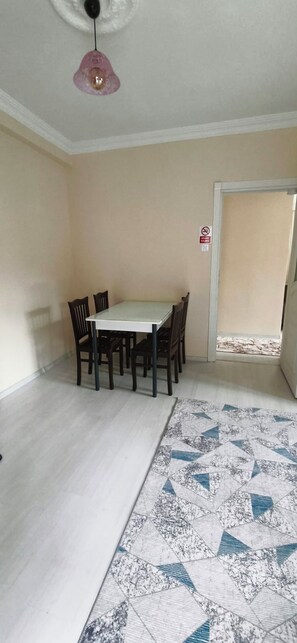 A dining area with a table and chairs, a patterned rug, a ceiling fan, and a window with a view. - YeşilKöy Pansiyon (Çamlıhemşin)