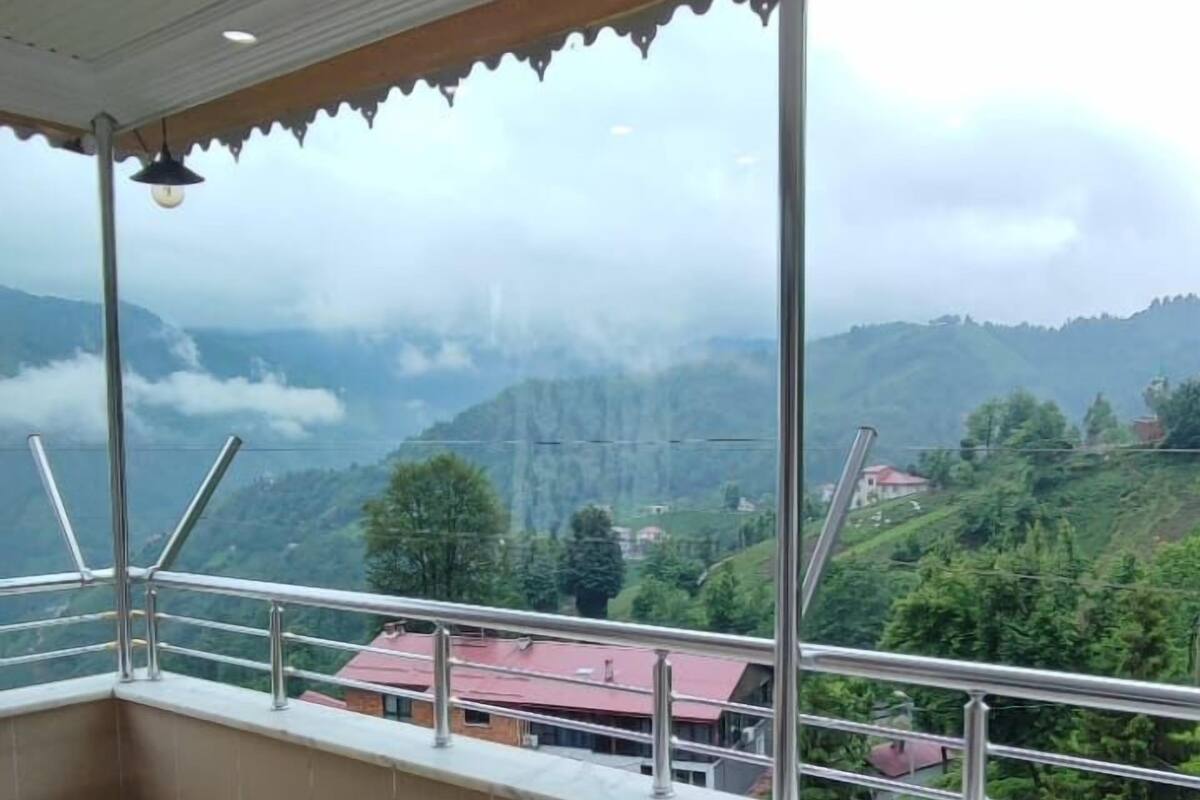 A balcony with a view of a mountainous landscape, a tiled floor, and a metal railing.