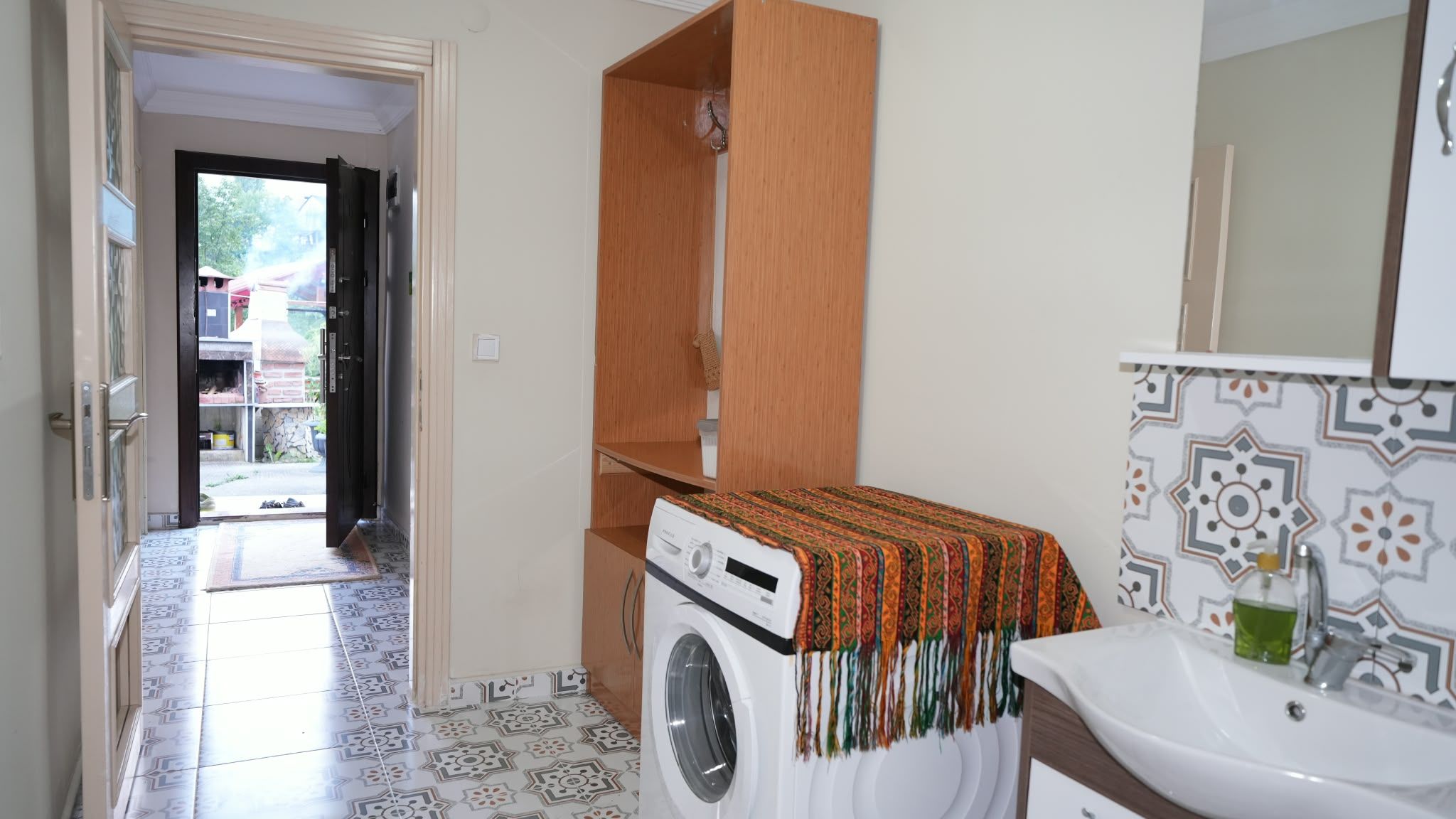 Une petite salle de bain équipée d’un lave-linge, d’un lavabo et d’un miroir.