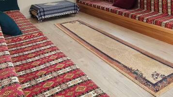 A spacious living area with a sofa set, a television, and a patterned rug.